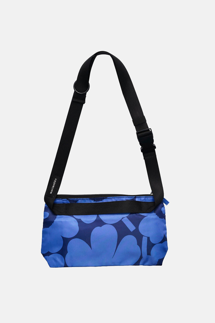 Blue patterned bag with a black strap on a light gray background