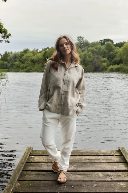 Woman standing on a wooden dock by a lake with trees in the background