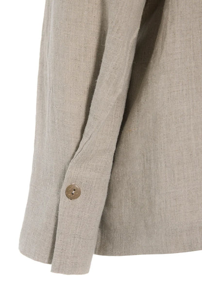 Close-up of a beige hemp shirt sleeve with a button on a white background
